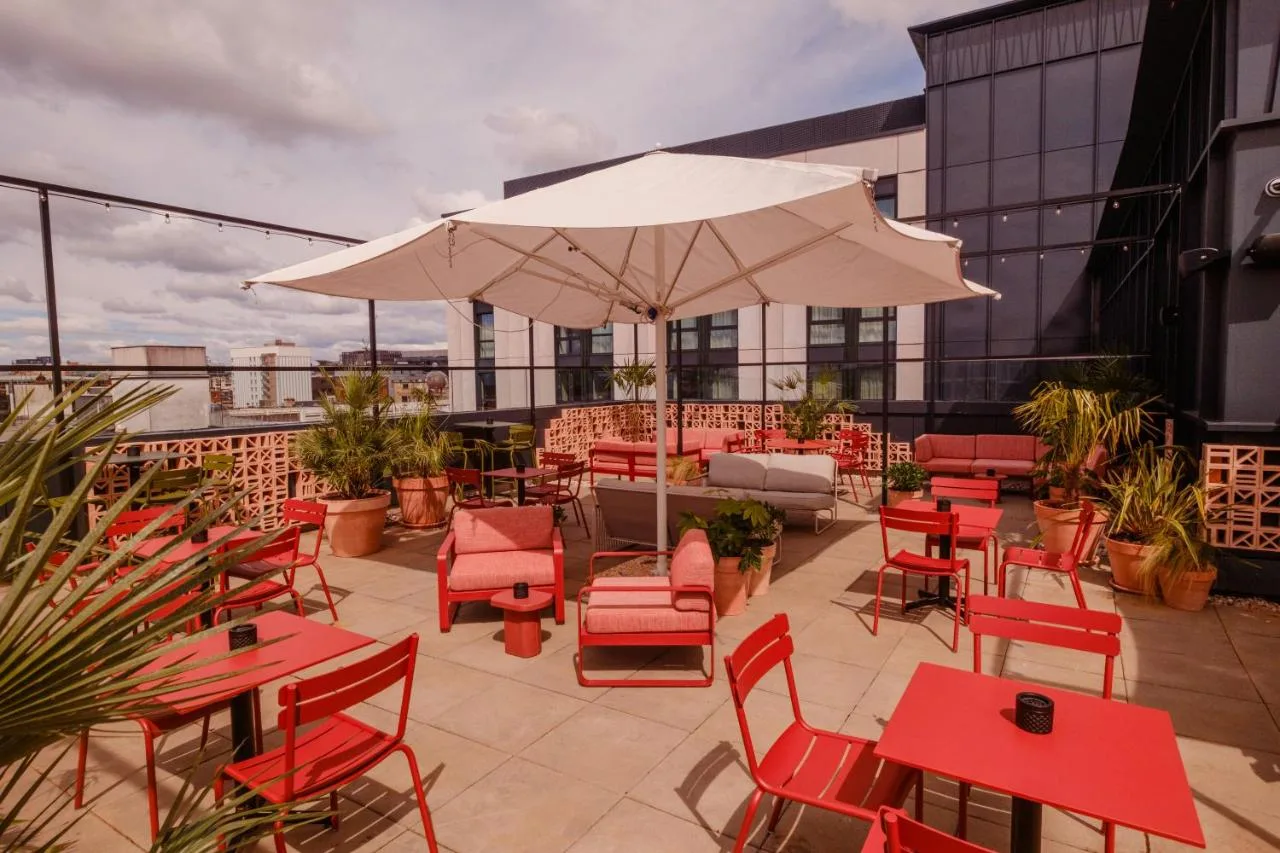 Terrace with red tables and white umbrellas at The Social Hub Glasgow